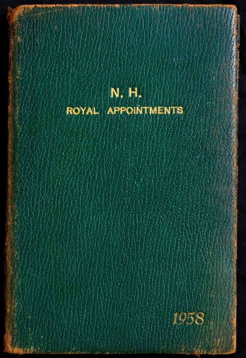 A close view of Norman Hartnell's royal appointments diary bound in green leather, 1958. Photographed against a white background.
