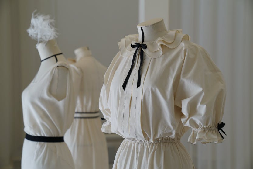 Mannequins displaying ivory toile dresses in an exhibition space