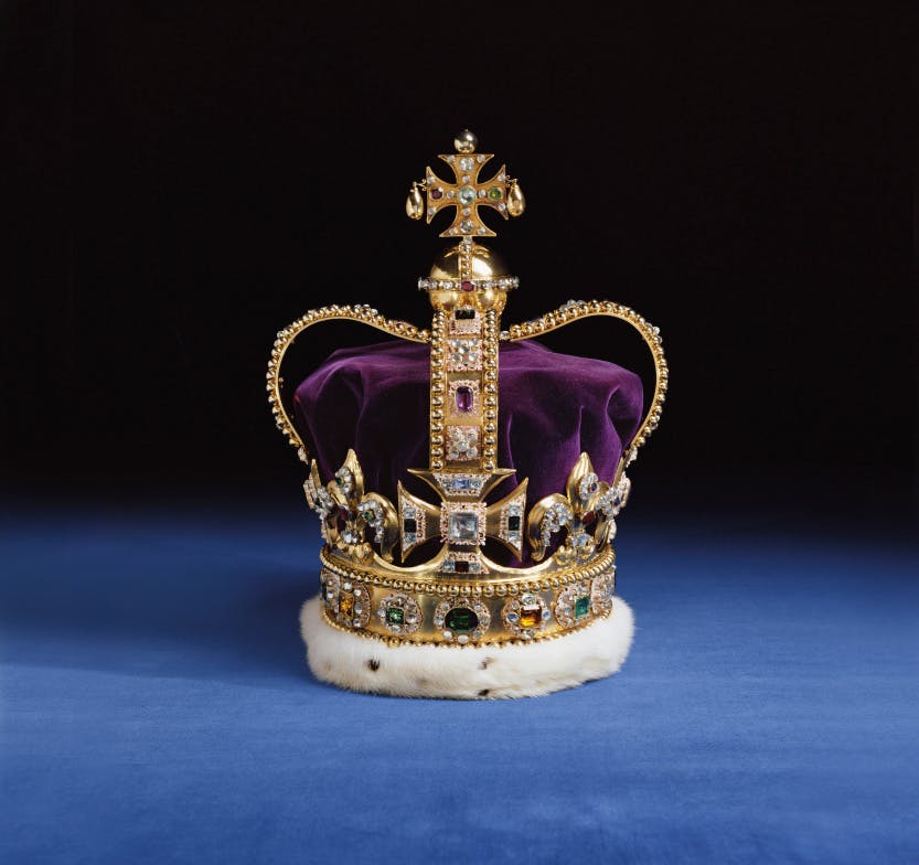 St Edward’s Crown with a gold frame set with semi-precious stones against a black and blue background.