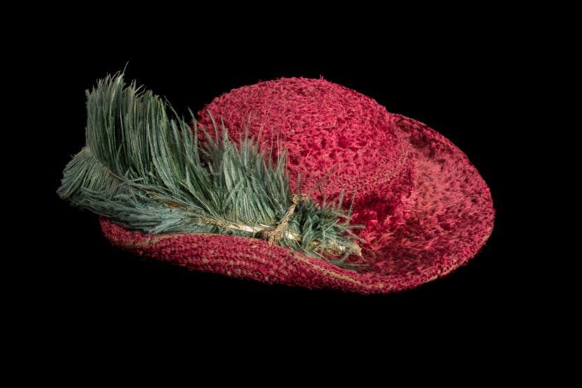 Tudor or early Stuart red hat with ostrich feather on black background.