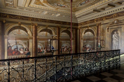 The staircase was painted by William Kent and completed in 1724. The walls depicts an elaborate arcaded gallery with figures behind a balustrade. Many are identifiable as members of King George I's court. The wrought iron balustrade is by Jean Tijou.