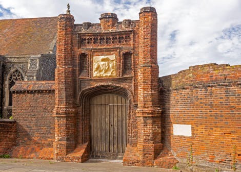 A red brick building with a gateway. The gateway is closed.