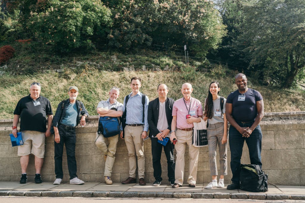 A group of people stand beside a road, smiling at the camera