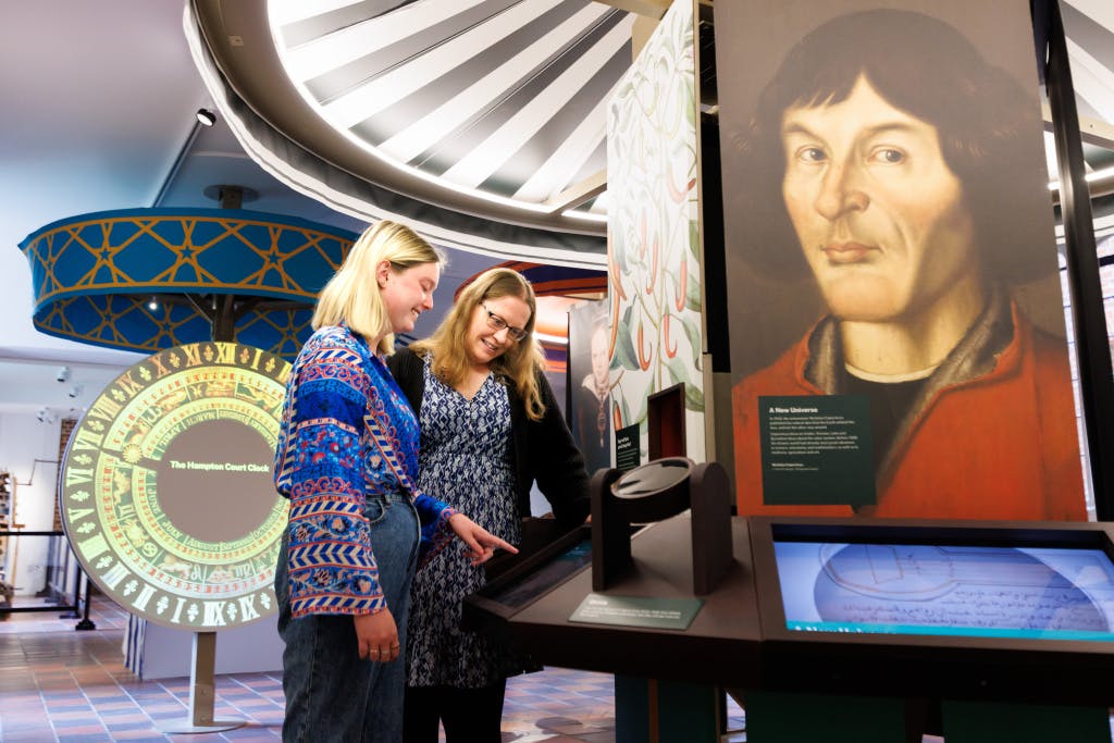 Two women in an exhibition space, interacting with an touch screen exhibit.