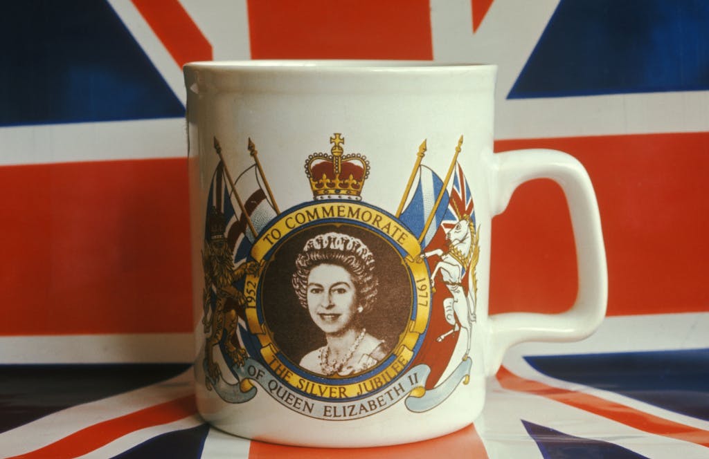 Queen Elizabeth II Silver Jubilee mug London England, 1977. Union Jack flag in the background.