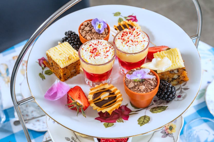 Images of mixed sweets and cake on a white floral plate.