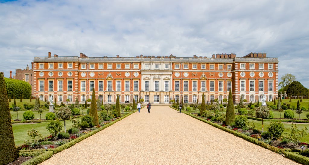 A wide gravel path leads down to a large 17th century palace between two areas of formal garden