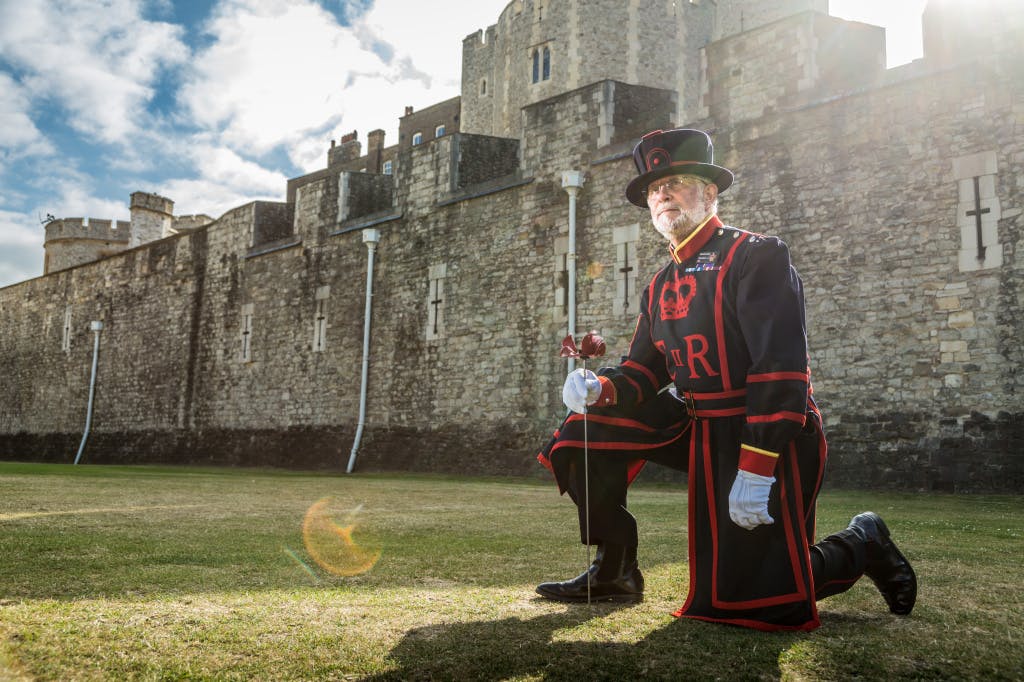 On 17 July 2014, Yeoman Serjeant Crawford Butler, then Tower of London's longest serving Yeoman Warder, planted the first of over 800,000 ceramic poppies that appeared around the famous landmark over the summer of 2014 to form a major art installation marking the centenary of the First World War. Yeoman Serjeant Crawford Butler kneels holding a ceramic poppy.