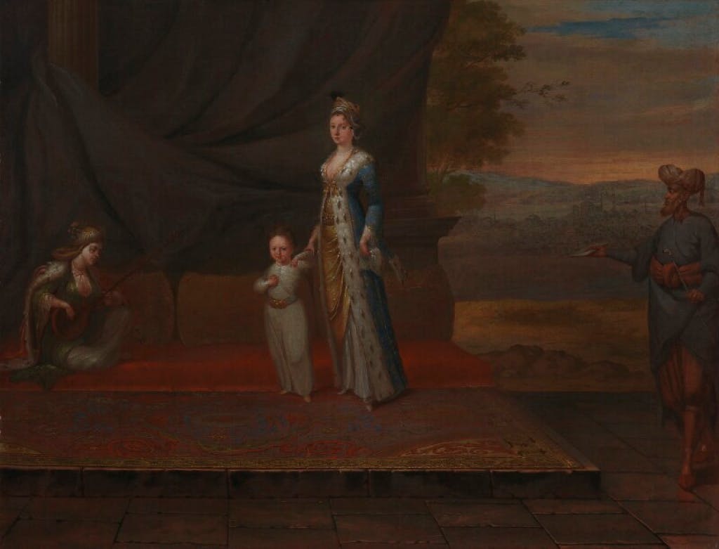 Portrait of a woman in a turquoise and gold dress, standing on a platform holding her young son. Two attendants stand on either side