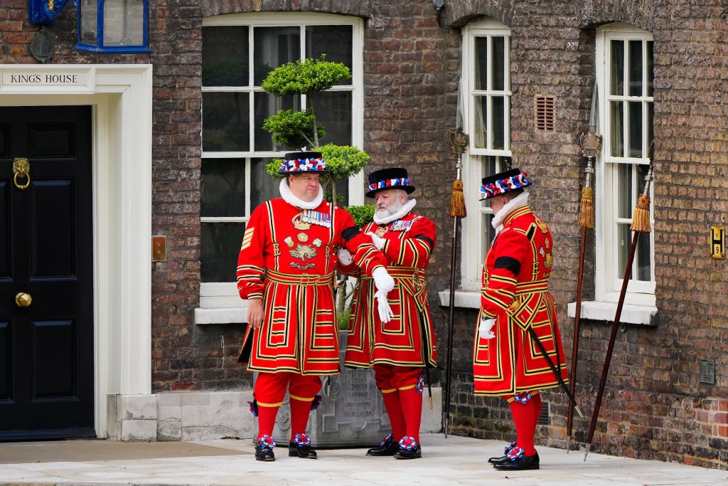 Three Yeoman help one another with mourning ribbons after the death of HRH Queen Elizabeth II