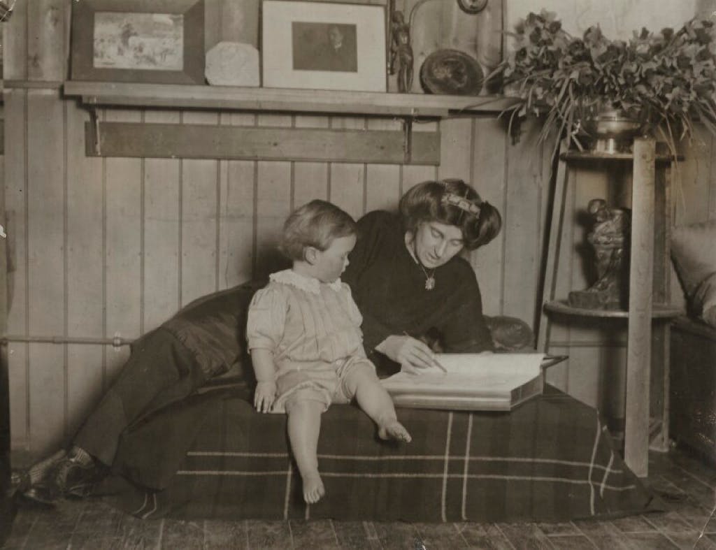 A black and white photograph of a woman showing a book to a young boy