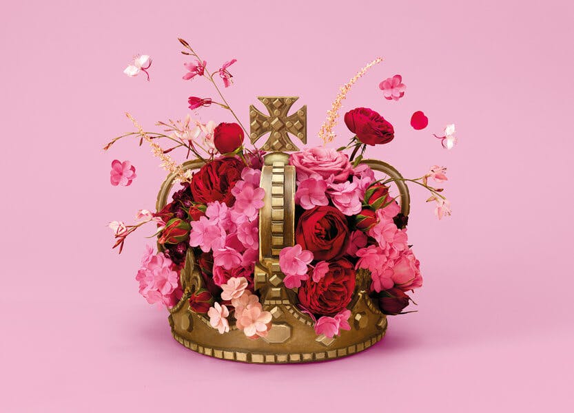 A gold crown sits on a bright pink background covered in pink flowers