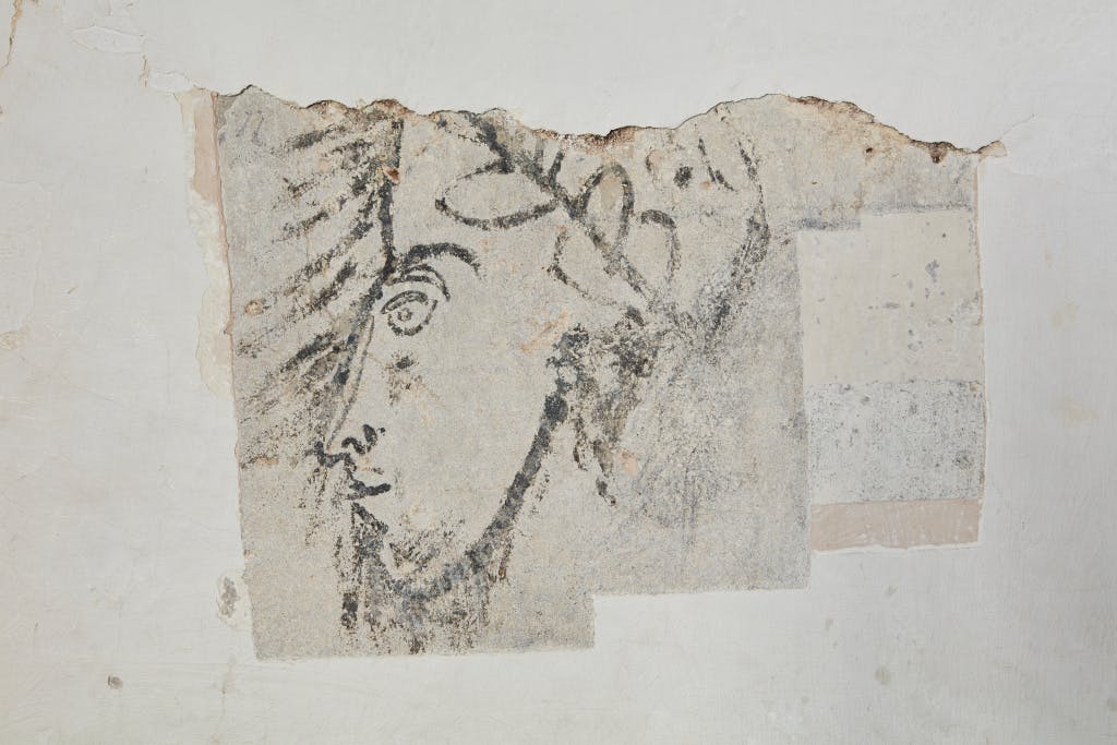 The Bloody Tower wall painting (room BLOSF001) 25 May 2018, looking south. Showing the uncovered section of a domestic black and white decorative scheme featuring a head drawn in thick black outline.