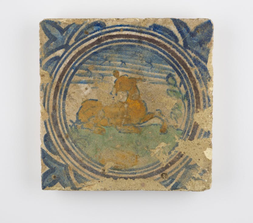 A ceramic tin-glazed tile, featuring a reclining deer, concentric circles and trefoil motifs, 1571-1615.