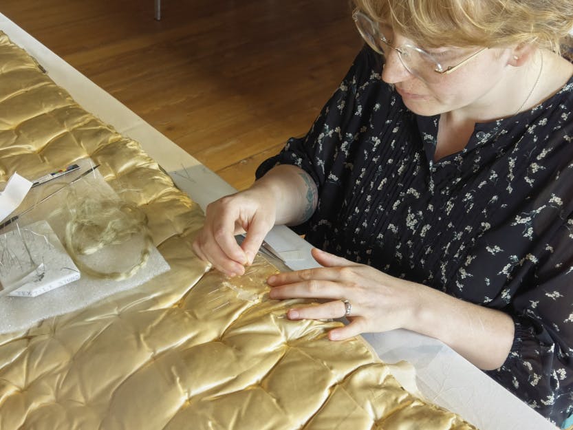 Conservation of the mattresses on Queen Caroline's State Bed: Conservator Rosie Chamberlin repairing the silk.