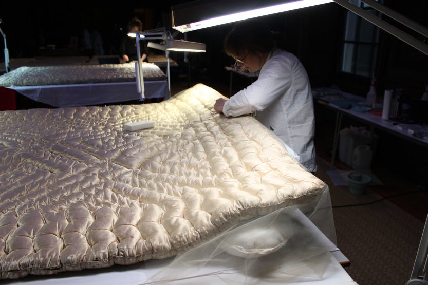 Conservation of the mattresses on Queen Caroline's State Bed: Conservator Beatrice Farmer repairing the quilting stitches.