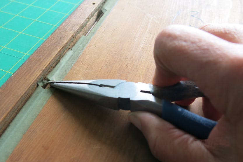 Close up of a Conservator's hand using pliers to remove a print frame.