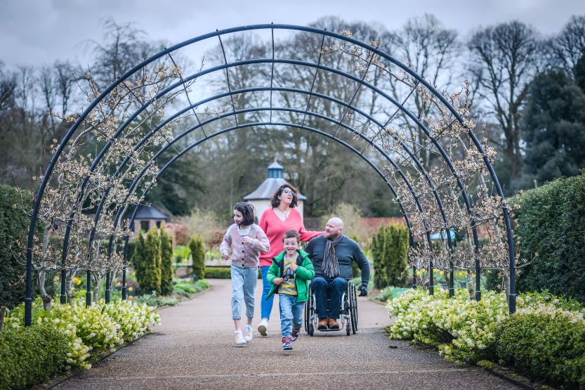 Family at Easter in Hillsborough Castle and Gardens- family  (man in wheelchair) enjoying Walled Garden as children search for hidden Easter bunnies.