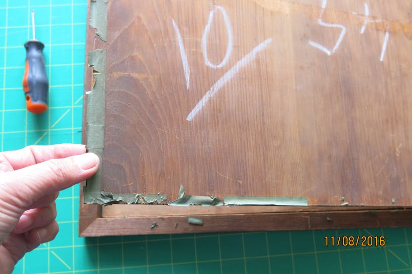 Close view of a Conservator's hand removing a wooden frame from a print.