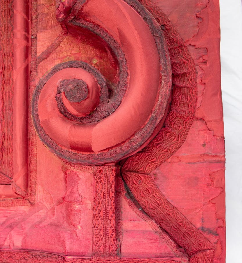 Conservation of the 18th Century headboard from Queen Caroline's State Bed. Showing a close view of 1980’s red damask and the original damask.