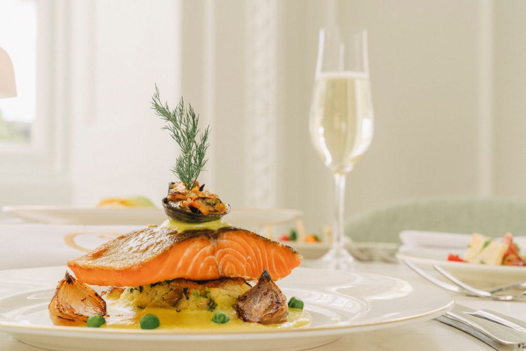 Plate of food, with salmon and a flute of champagne.