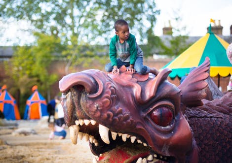 Boy playing on the large dragon sculpture in the Magic Garden