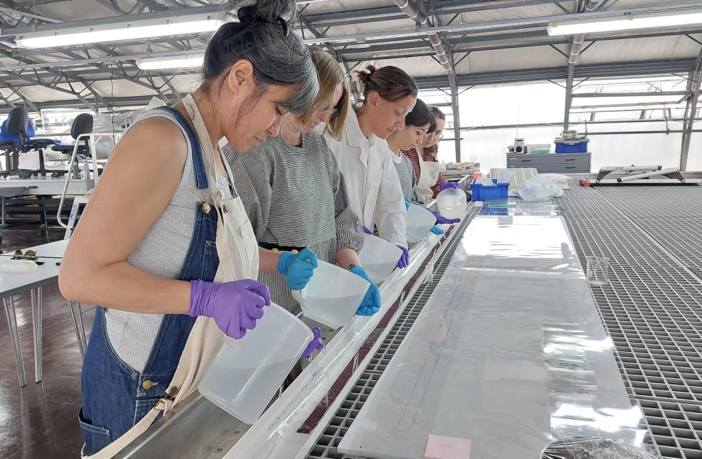 A team of conservators in a conservation studio wet cleaning a piece of fabric