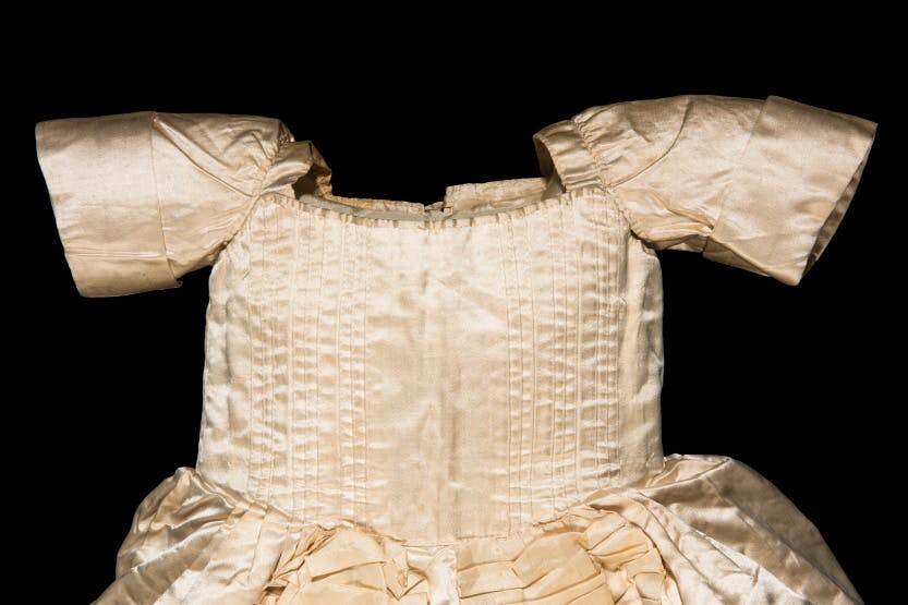 A hand-stitched, fine silk robe worn by George, Prince of Wales (later Prince Regent, then King George IV) (1762-1830). Showing the bodice of the robe. Photographed on a black background.